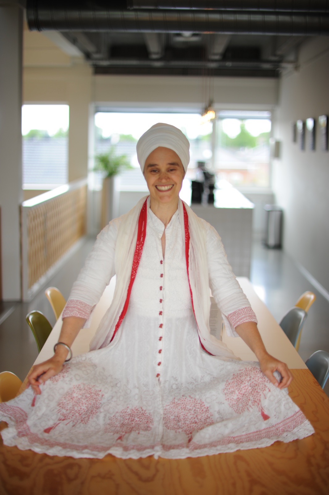 Sat Kirtan Kaur Khalsa, dressed in white with a white turban, smiling